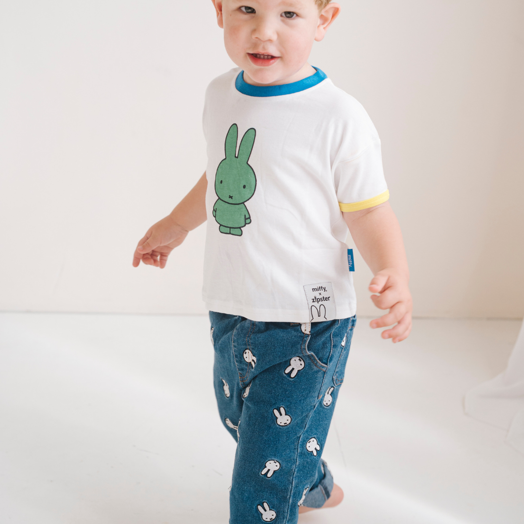 Kind, das das weiße Miffy Kinder-T-Shirt mit grünem Miffy Aufdruck trägt